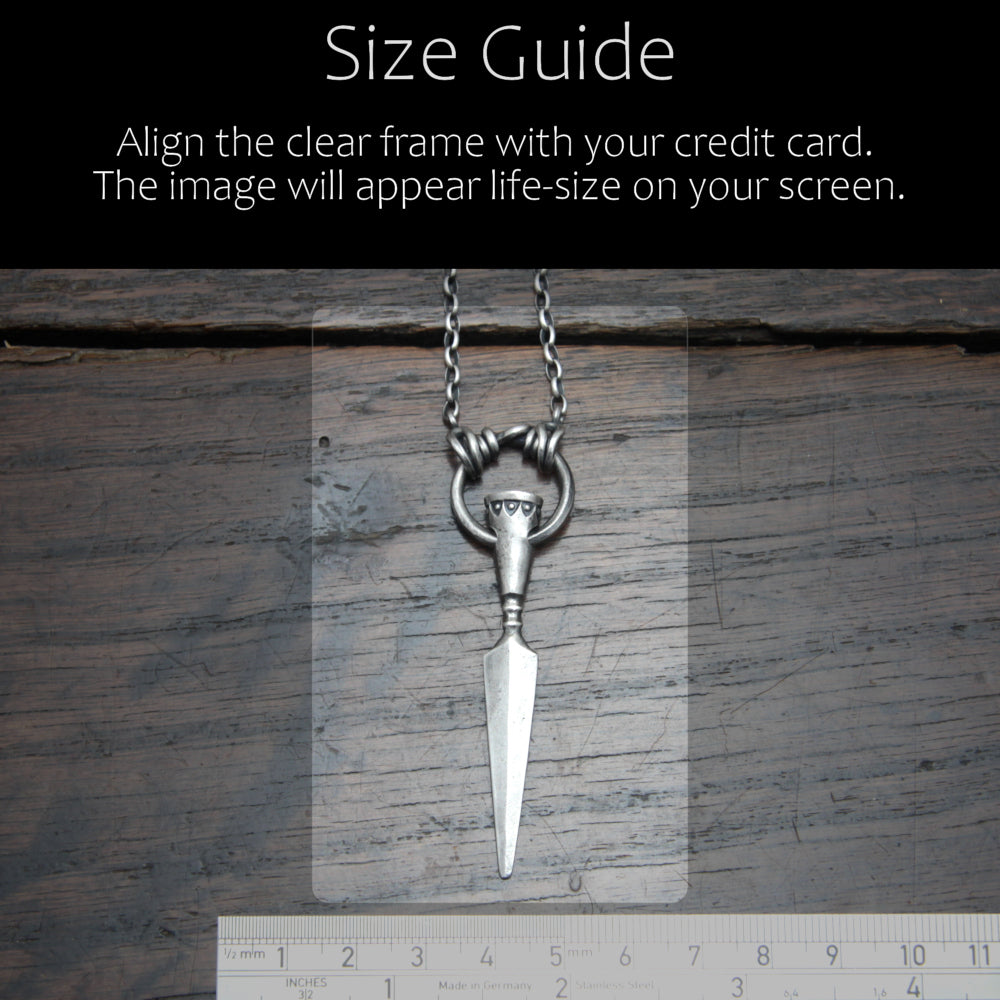 Size reference photo of the silver spear pendant compared to a credit card for scale.