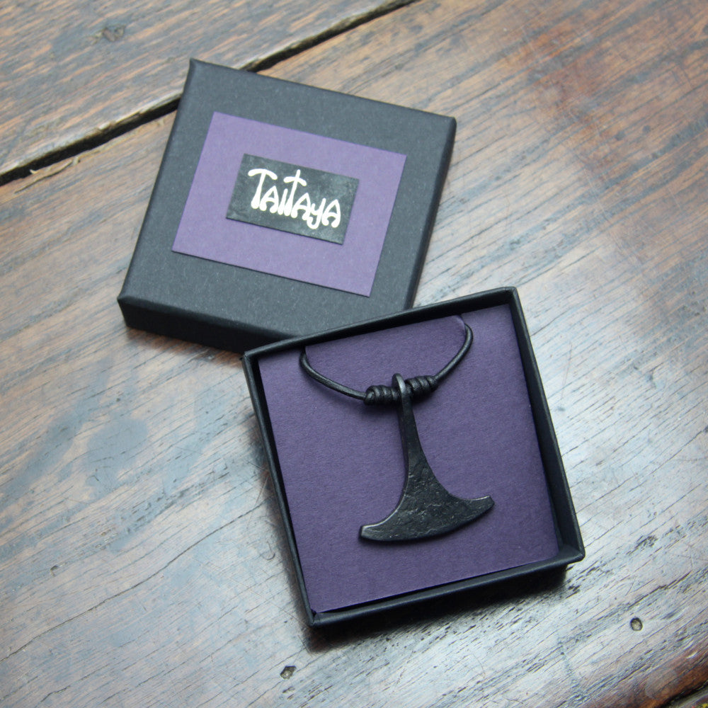Hand forged small iron Ukonvasara pendant made by taitaya forge, presented in a black card gift box with gold embossed branding and purple insert card. 